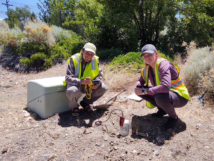 two researchers installing seismometer in ground