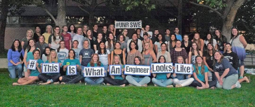 People on grass holding up signs that read #UNRSWE and #ThisIsWhatAn EngineerLooksLike.