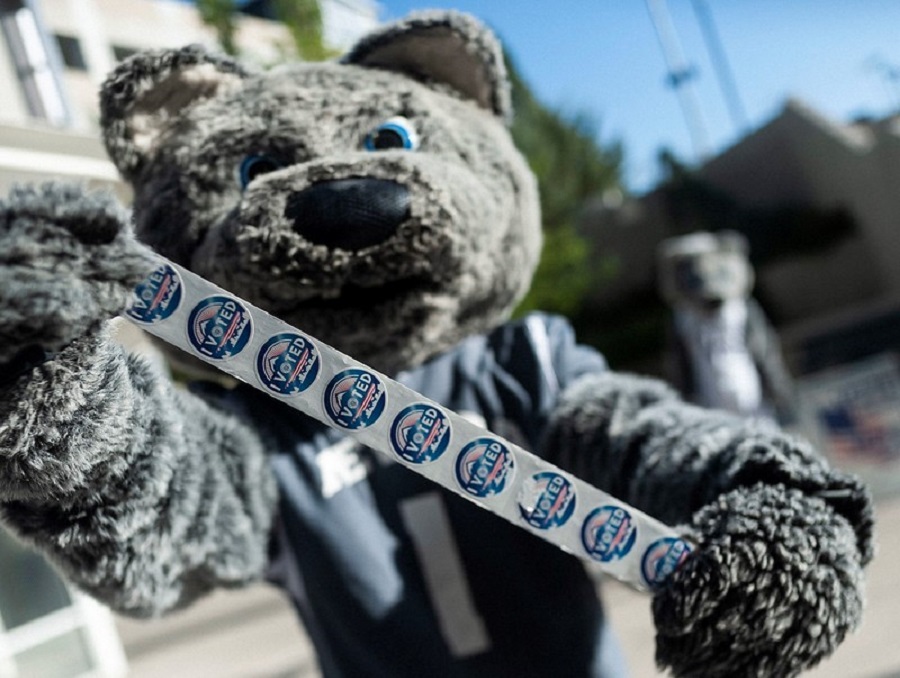 Alphie, Jr., the Wolf Pack mascot, holds up a roll of "I voted" stickers