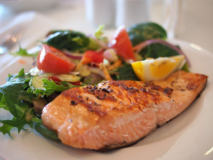 A plate of cooked salmon with vegetables.