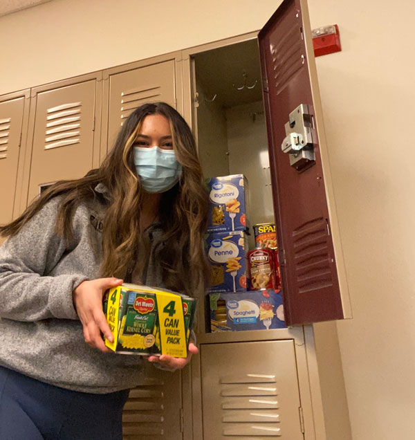 Orvis nursing student holding food items and showing locker of food and supplies