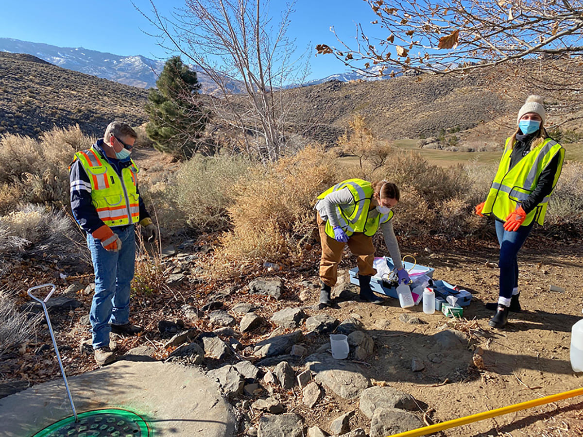 students in reflective vests working in the field on a sunny day.