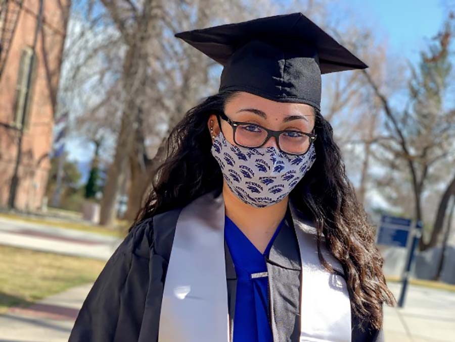 University of Nevada, Reno graduate with grad cap and facial covering on the historic Quad