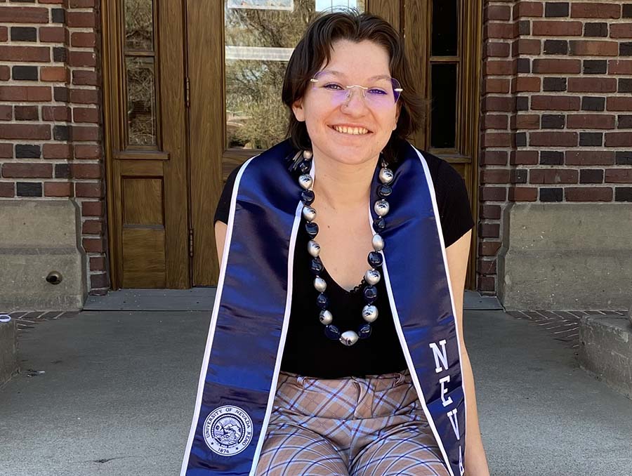 Senior Scarlett Boling sits on steps smiling for graduation pictures