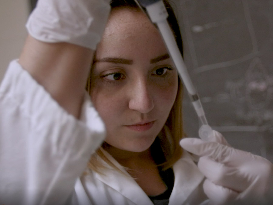 A biochemistry student using a syringe to measure out a liquid.