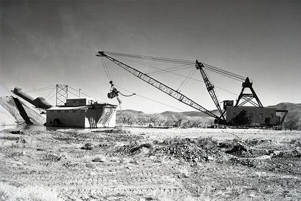 black and white photo of gold dredges like the types used in Dayton were large placer mining machines used to excavate and extract gold from sand, gravel, and dirt using water and mechanical methods. These dredges could weight up to 900-tons.