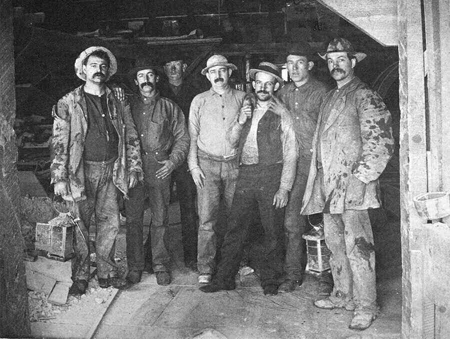 Group of seven miners stand at the entrance of a mine located in Nevada