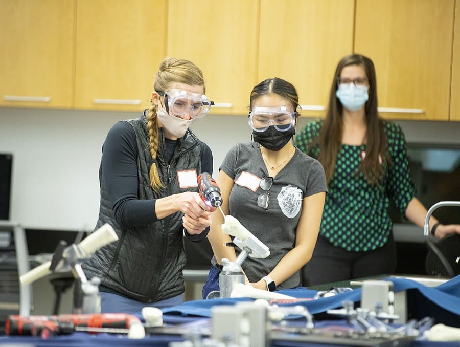 Students working on a project using a drill on a lab table
