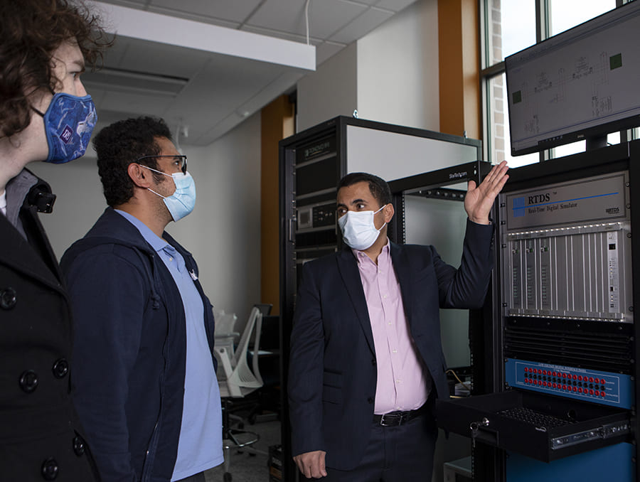 Ben-Idris with two students in front of machinery