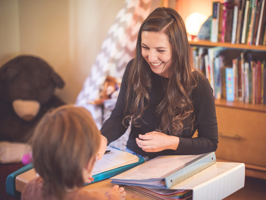 Staheli Meyer sits at a table with a young child in the foreground and binders on the table between them.