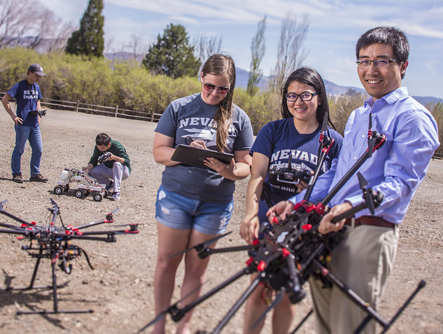 Hao Xu and students with several drones on a sunny day