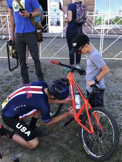 Luke Miers fixes his mountain bike with the assistance of a young person.