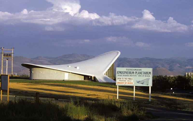 The planetarium with a sign in the foreground advertising the planetarium.