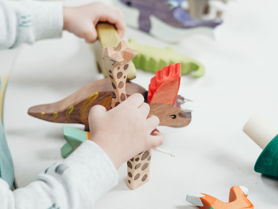 A child's hands are shown playing with wooden toys.