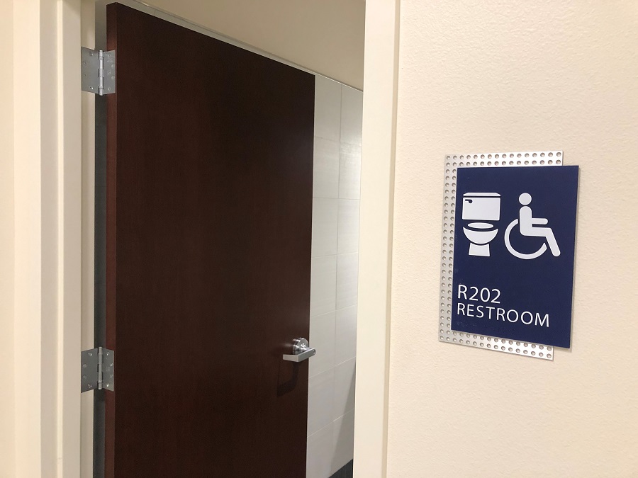 A restroom marked with new gender-inclusive signage and the door open