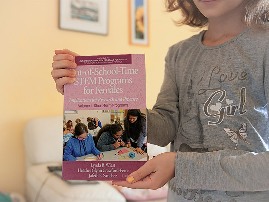 Student holding a book for the camera