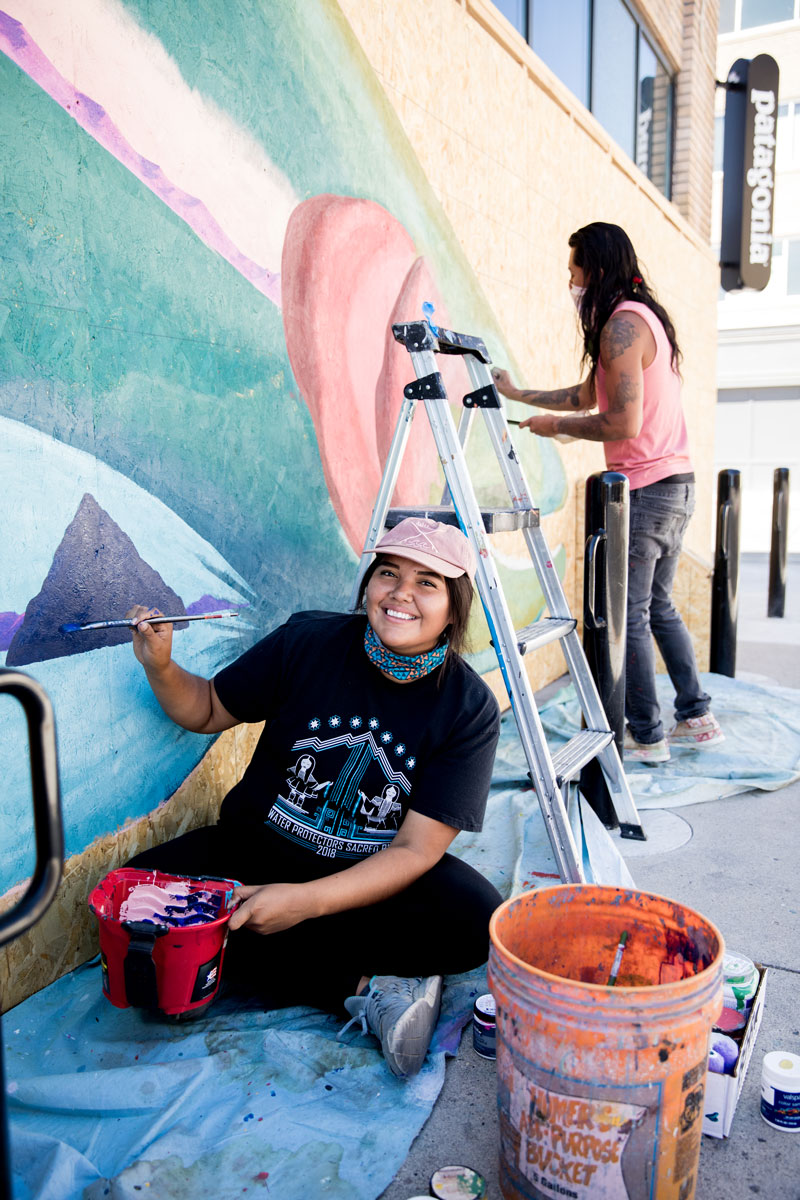 Autumn Harry paints a mural of a fish.