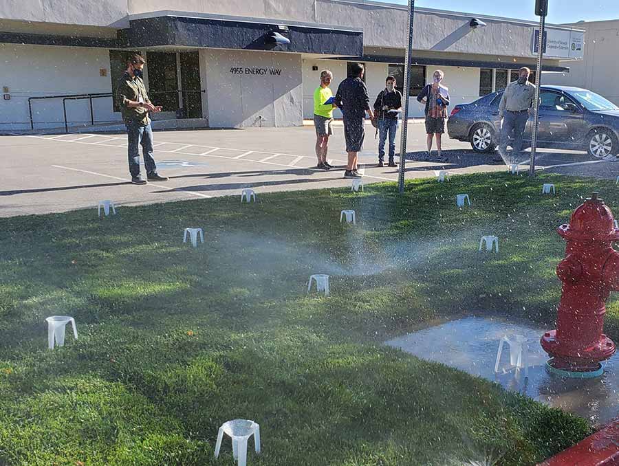 A group gathered around sprinklers for QWEL training. 