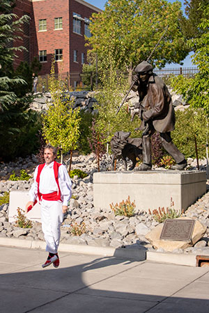 Basque dancer wearing traditional attire dancing underneath statue outside