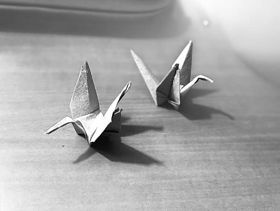 Black and white image of origami cranes made from retired military uniforms