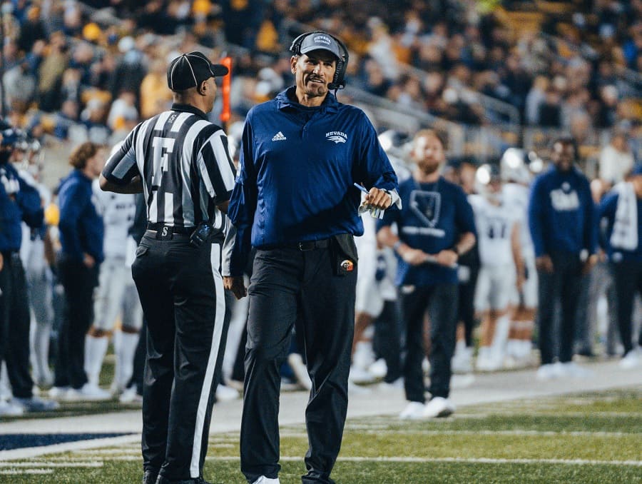 Coach Jay Norvell talking to a ref on the football field during a game