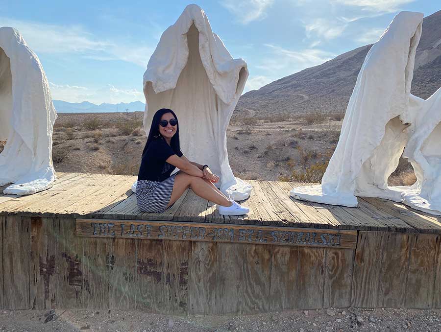 Jennifer Burton sitting on the ledge in front of art sculptures