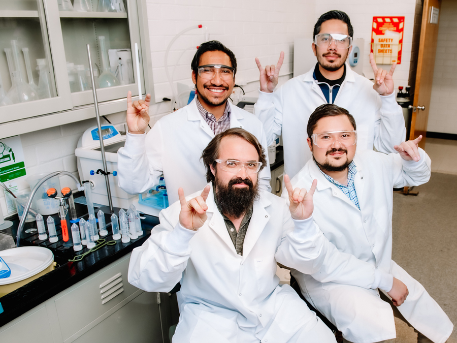 Four University alumni pose in UNR lab.
