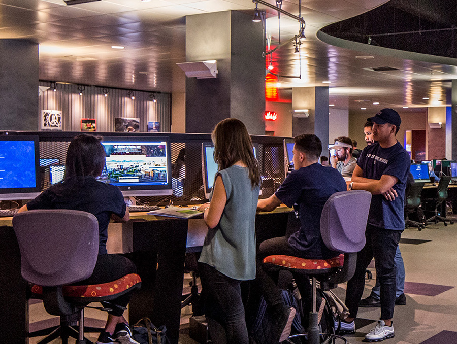 Six students looking at three computer monitors, backs to the camera.