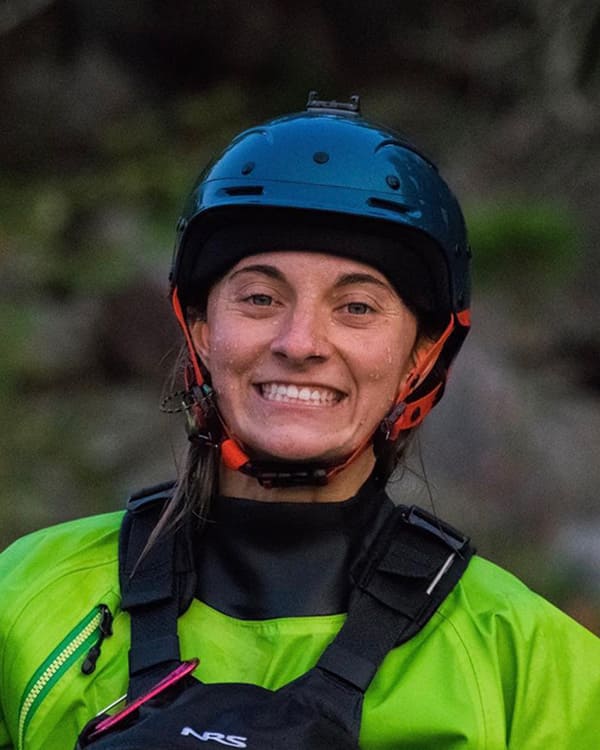 Brooke Hess wears a green jacket and a helmet and smiles to camera.