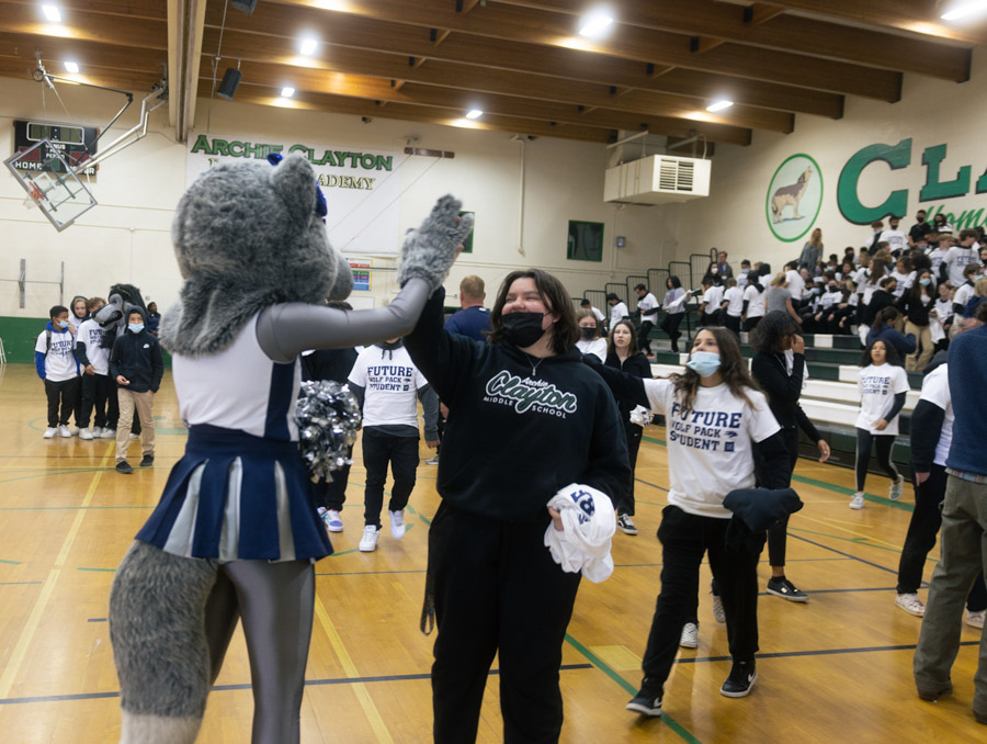 A Clayton middle-schooler gives a high-five to Luna, the Nevada Wolf Pack mascot, in the Clayton gym.