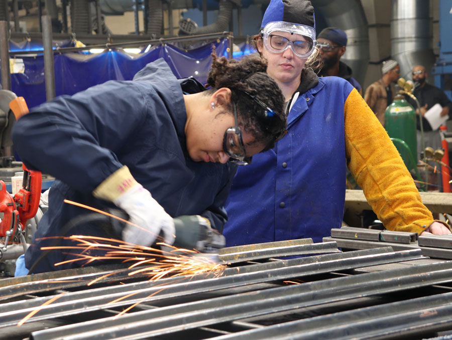 Two manufacturing workers using a grinding tool.