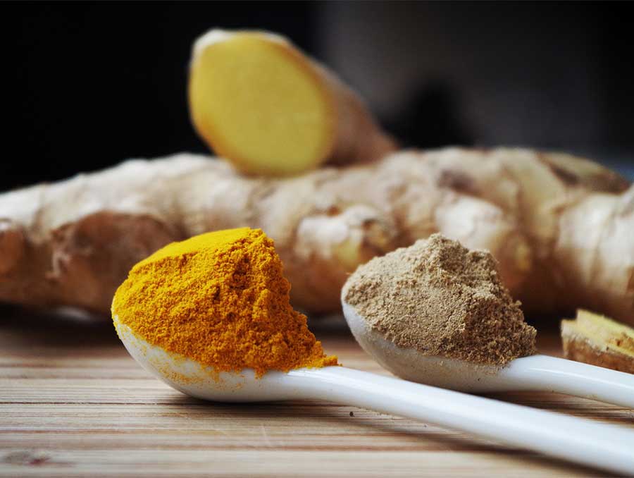 Ginger root with spoons of powdered spices.