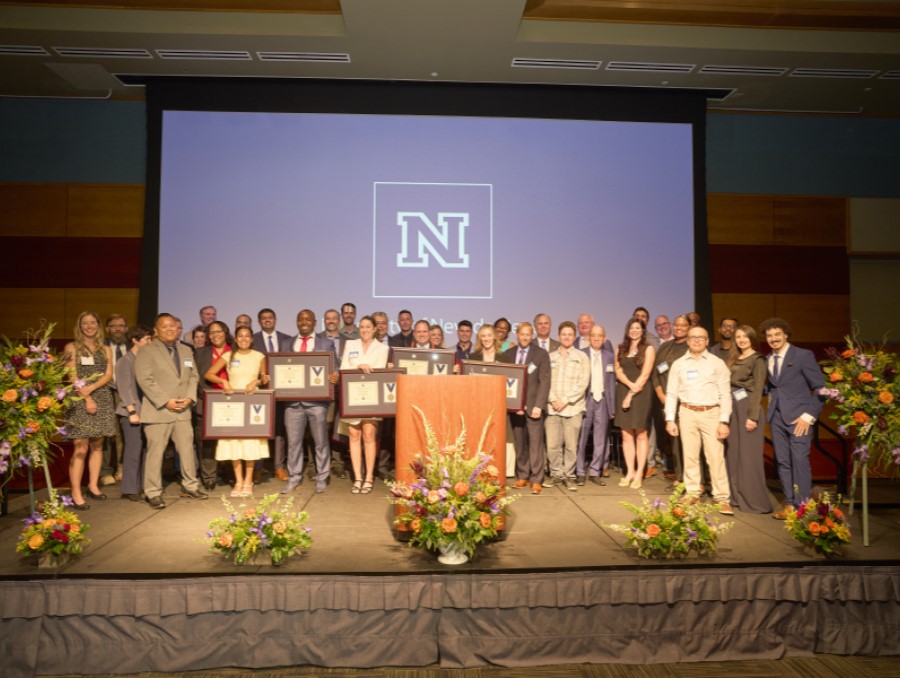 A group of recent EMBA graduates from the University of Nevada, Reno stand together on stage.