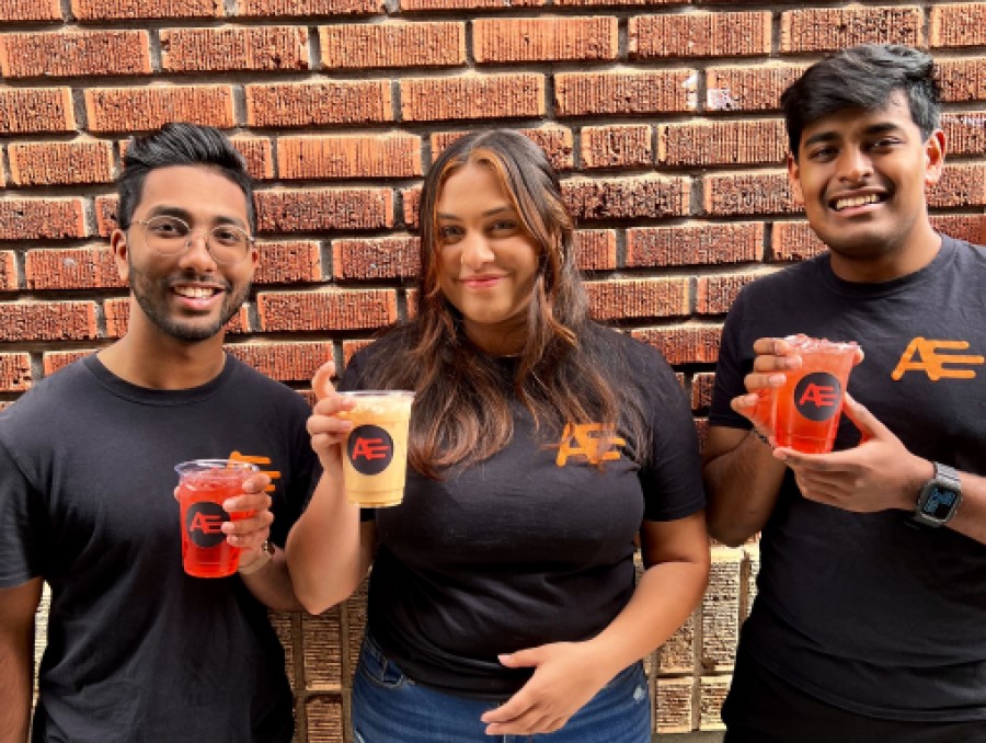 The founders of AYCE Delivery stand together in front of a brick wall