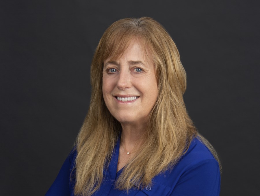 Photograph of Winnie Dowling wearing a blue shirt in front of a gray background