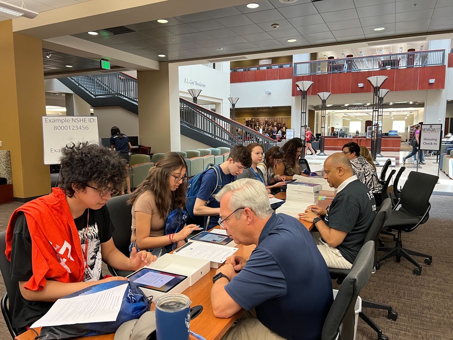 NevadaFIT students open iPads at long tables with mentors during NevadaFIT inside the Knowledge Center.