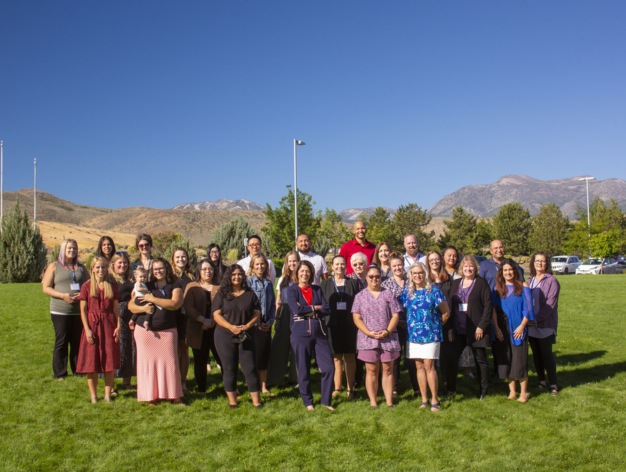 Interim Dean, Lillian Wichinsky, stands smiling with others from the School of Social Work on a grassy lawn on a sunny day. 