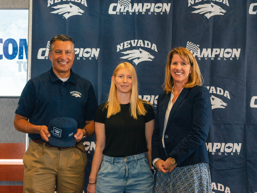 University of Nevada, Reno President Brian Sandoval poses holding a Nevada Skiing branded baseball hat along with Nevada Skiing coach Mihaela Kosi and Nevada Athletics Director Stephanie Rempe in front of a Nevada Athletics and Champion Chevrolet backdrop. 