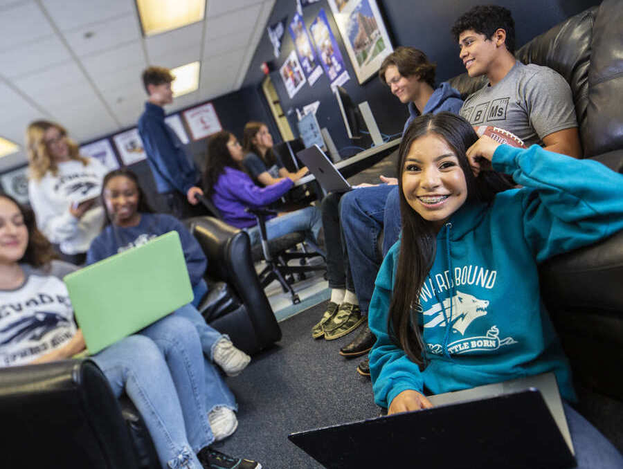 A group of students wearing upward bound sweatshirts study and smile