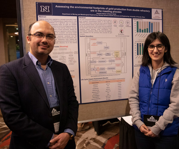 Ehsan Vahidi and Saeede Kadivar stand in front of Saeede's poster. Both are smiling.