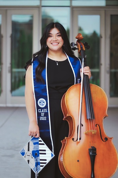 Nicole poses with her cello outdoors and in graduation regalia.
