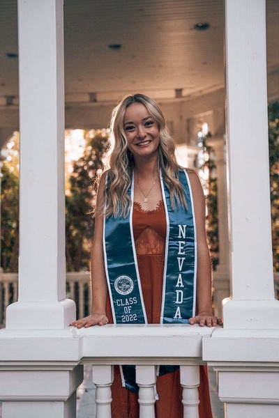 Megan Perry poses outside in graduation regalia