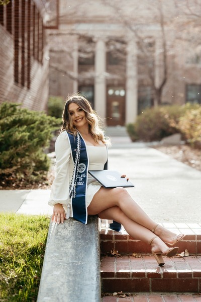 Gabrielle poses outside in graduation regalia.