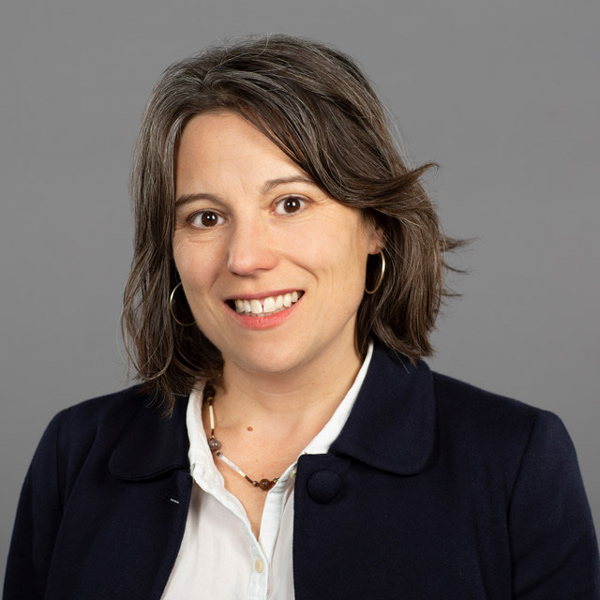 Stephanie McAfee smiles, wearing a blazer over a white collared shirt.