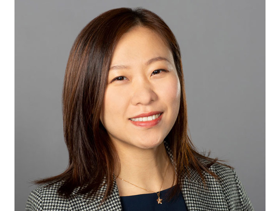 Ying Yang wearing a patterned blazer smiles in her headshot.