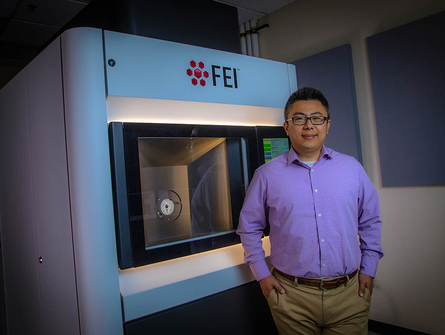 Yufeng Zheng standing in front of lab equipment.