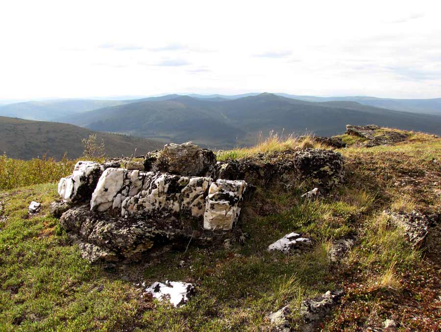 Thick quartz veins cut across outcrops of granitic gneiss on a grassy hilltop.