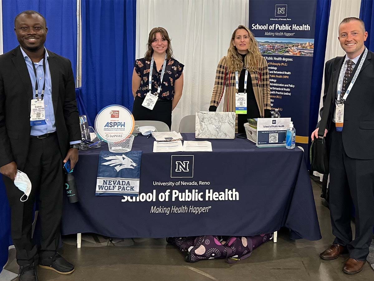 Associate Professor Eric Crosbie, doctoral students Luciana Borges and Olufemi Erinoso, and MPH student Sara Perez, standing at the School of Public Health table.