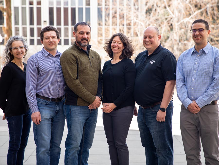 The principle investigators of the project stand in a line, smiling in front of the Effie Mona Mack building.