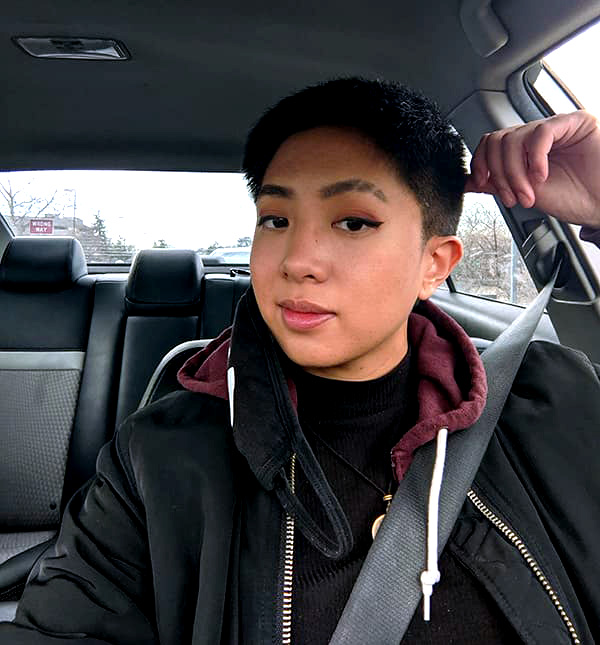 Lynn Lazaro smiles to camera while sitting in a car.